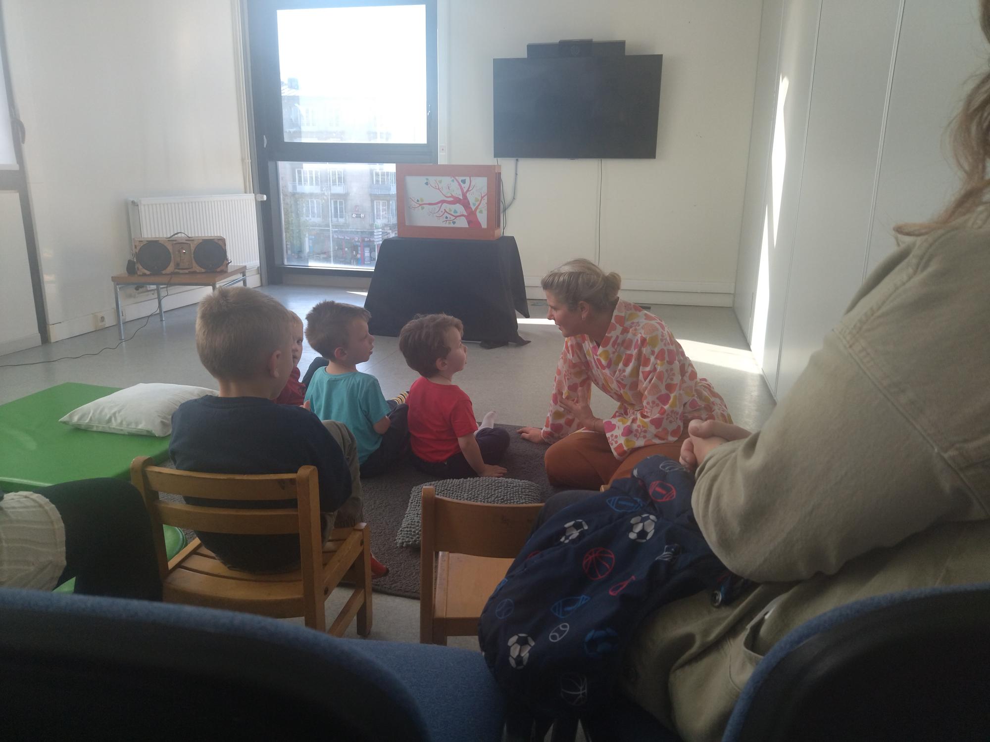 Comédienne assise devant des enfants 